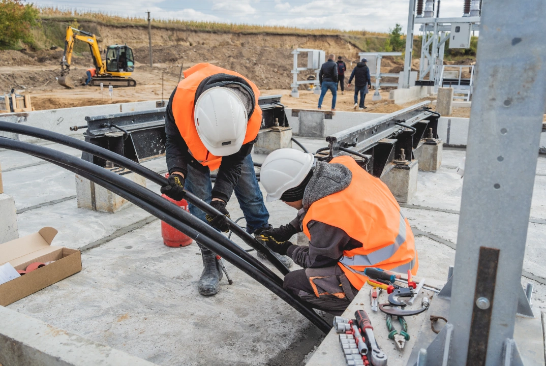 Two electrician workers installing voltage cable